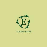 bokstaven e alfabetisk logotyp formgivningsmall isolerad på grön beige färg. dekorativa blommiga sköld tecken illustration. naturvakt, säkerhetslogotyp koncept. vektor