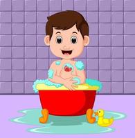 Junge, der in einer mit Blasen gefüllten Badewanne in einem Badezimmer sitzt