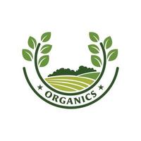 Dieses Bild ist ein Logo-Emblem, das eine Landschaft eines landwirtschaftlichen Feldes in grüner Farbe inmitten eines Lorbeerkranzpaares darstellt, das als Etikettenlogo für Bio-Bauernhofprodukte verwendet werden kann