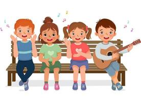 Fröhliche kleine Jungen und Mädchen klatschen in die Hände, singen, spielen Gitarre und haben Spaß zusammen auf der Bank sitzend