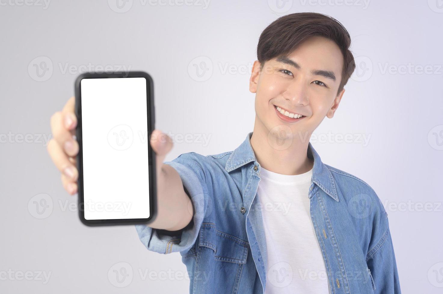 jeune homme asiatique utilisant un smartphone sur fond blanc, concept technologique. photo