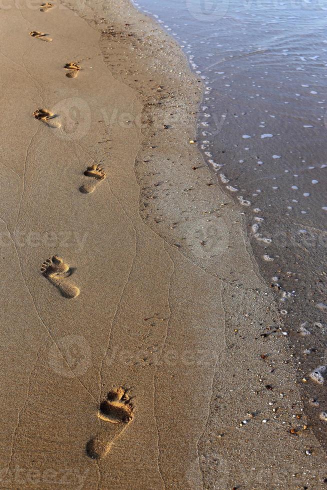 empreintes de pas dans le sable sur la plage de la ville. photo