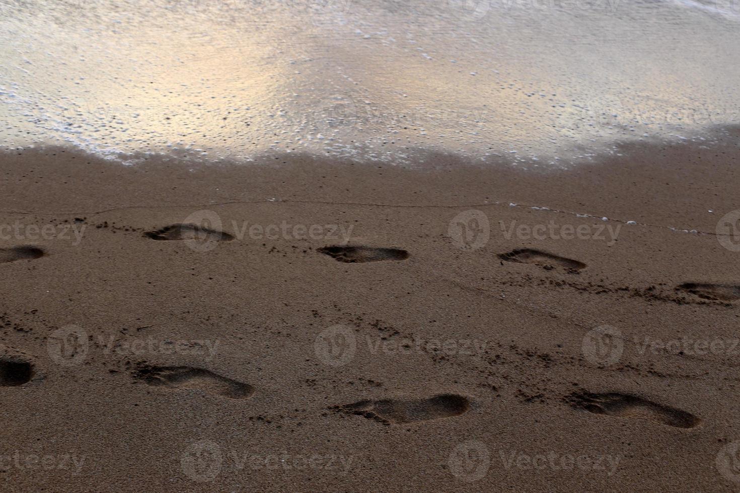 empreintes de pas dans le sable sur la plage de la ville. photo