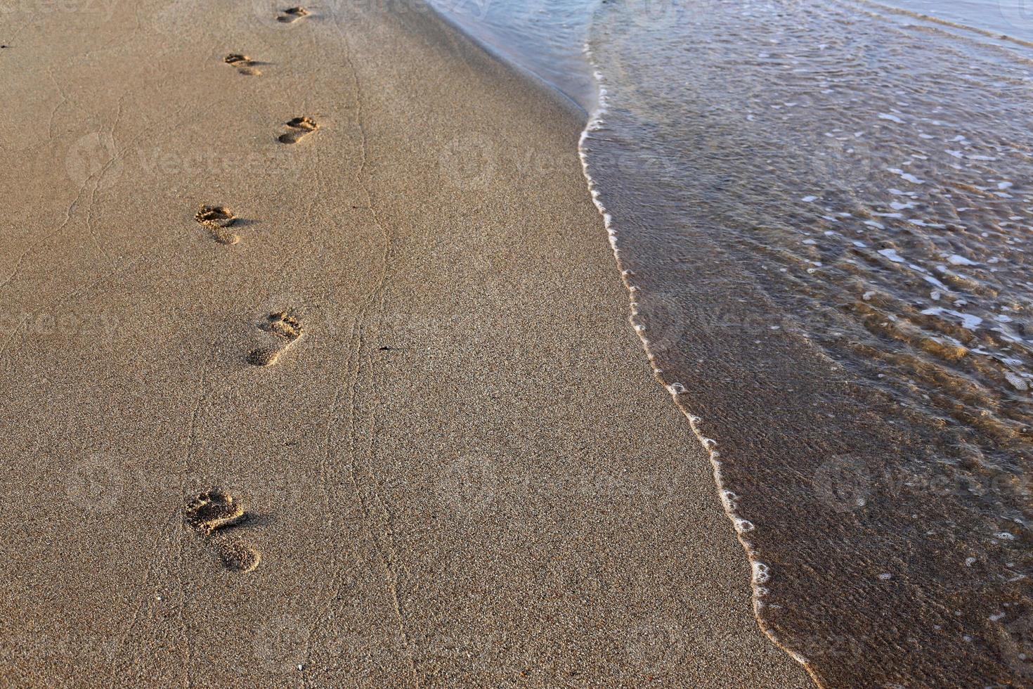 empreintes de pas dans le sable sur la plage de la ville. photo