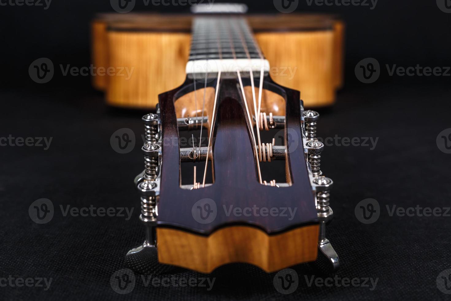 Chevilles de réglage en bois sur tête de machine de six cordes manche de guitare acoustique sur fond noir photo