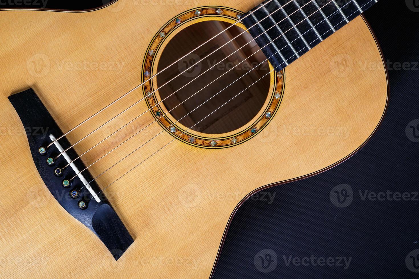 texture bois du pont inférieur de la guitare acoustique à six cordes sur fond noir. forme de guitare photo