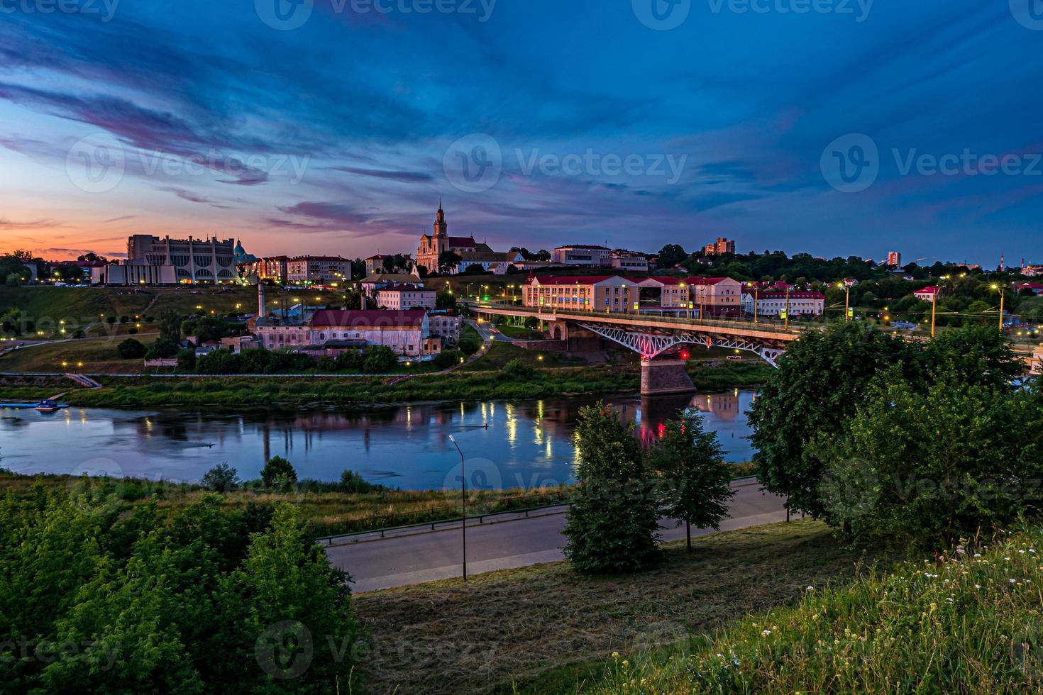 vue panoramique le soir dans la vieille ville sur la rive d'une large rivière avec des nuages de cirrostratus bouclés et bouclés du soir et un ciel bleu violet rouge coucher de soleil en arrière-plan photo