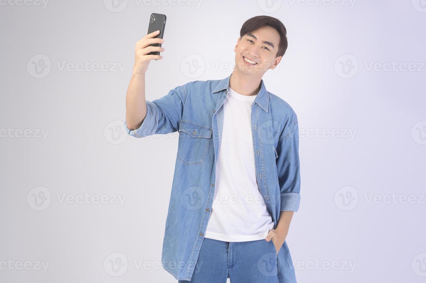 jeune homme asiatique utilisant un smartphone sur fond blanc, concept technologique. photo