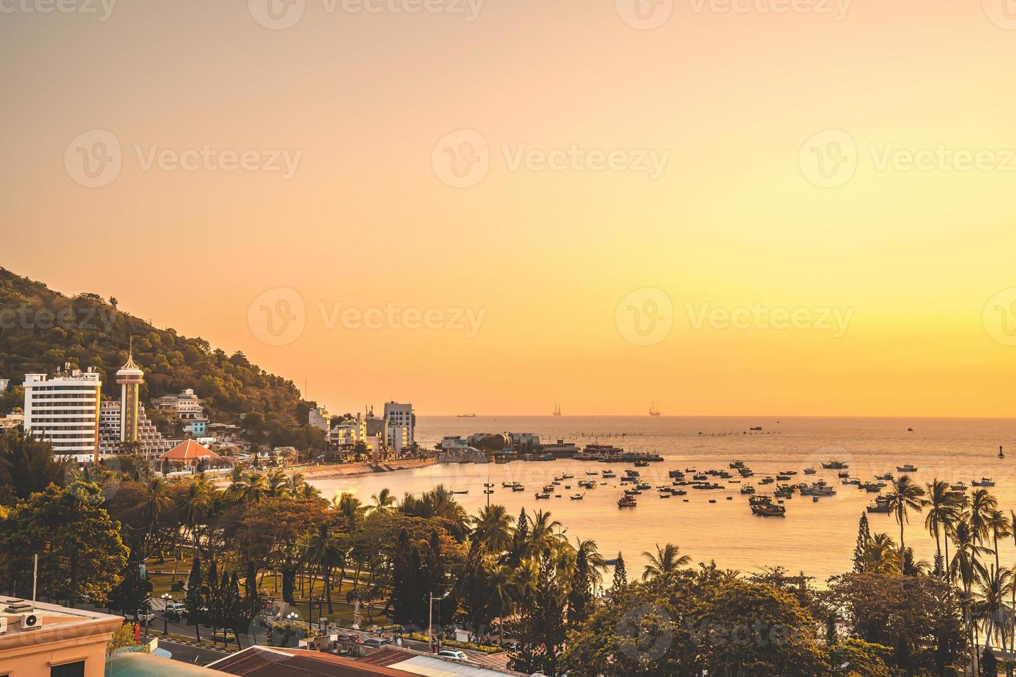 vue aérienne de la ville de vung tau avec un beau coucher de soleil et tant de bateaux. vue panoramique sur la côte vung tau d'en haut, avec vagues, littoral, rues, cocotiers et montagne tao phung au vietnam. photo