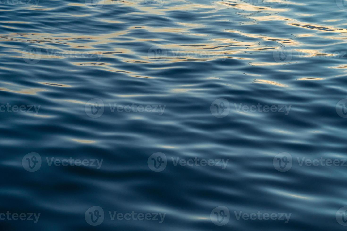 l'eau du coucher du soleil reflète les ondulations à la lumière du soleil. réflexion dorée abstraite sur le coucher du soleil sur l'eau photo