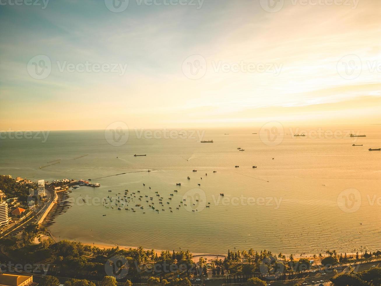 vue aérienne de la ville de vung tau avec un beau coucher de soleil et tant de bateaux. vue panoramique sur la côte vung tau d'en haut, avec vagues, littoral, rues, cocotiers et montagne tao phung au vietnam. photo