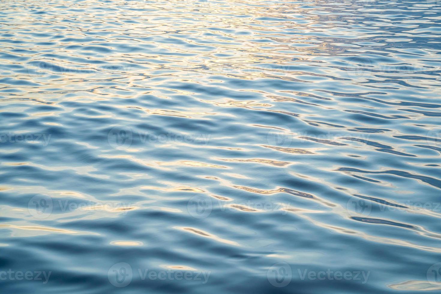 l'eau du coucher du soleil reflète les ondulations à la lumière du soleil. réflexion dorée abstraite sur le coucher du soleil sur l'eau photo
