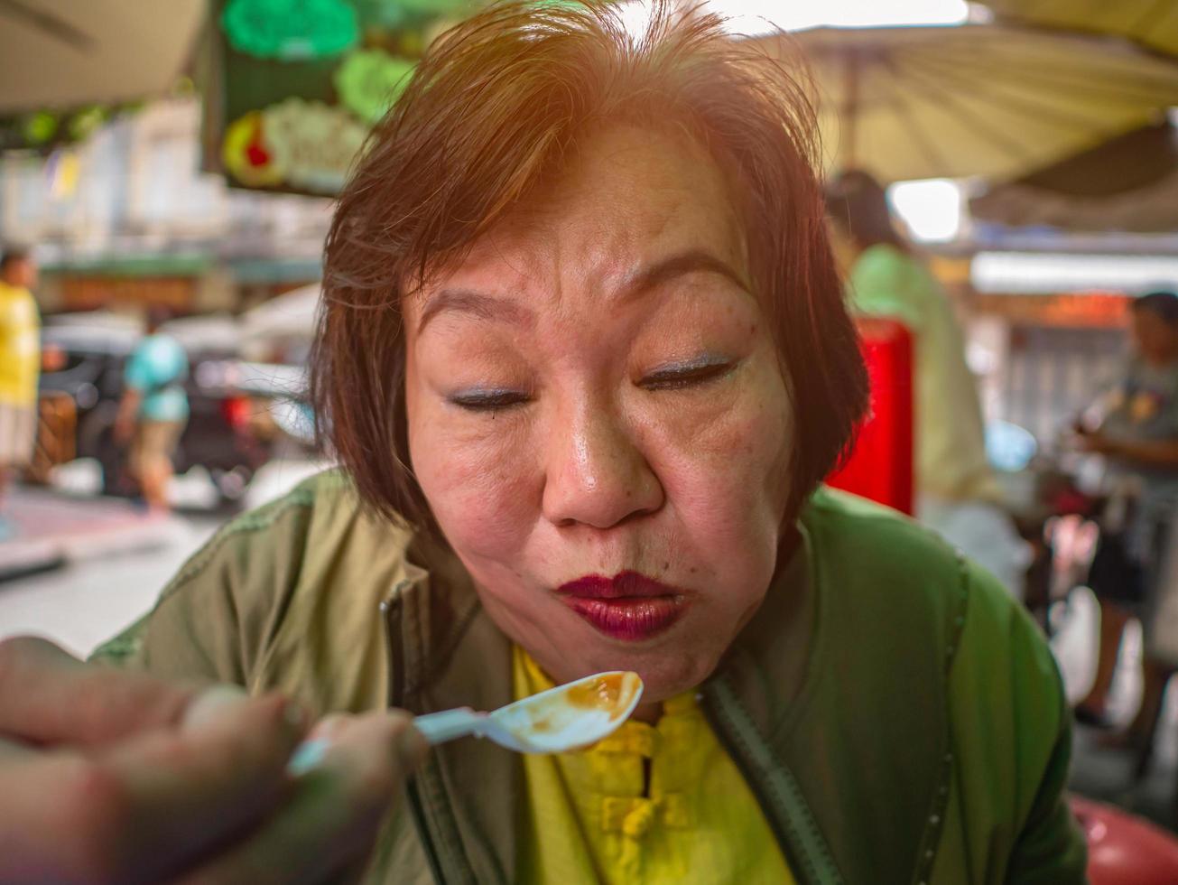 les vieilles femmes asiatiques heureuses qui mangent ont l'air très délicieuses photo