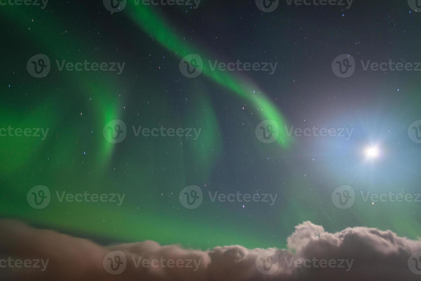 les aurores boréales au-dessus du ciel contre la lumière de la pleine lune en islande. photo