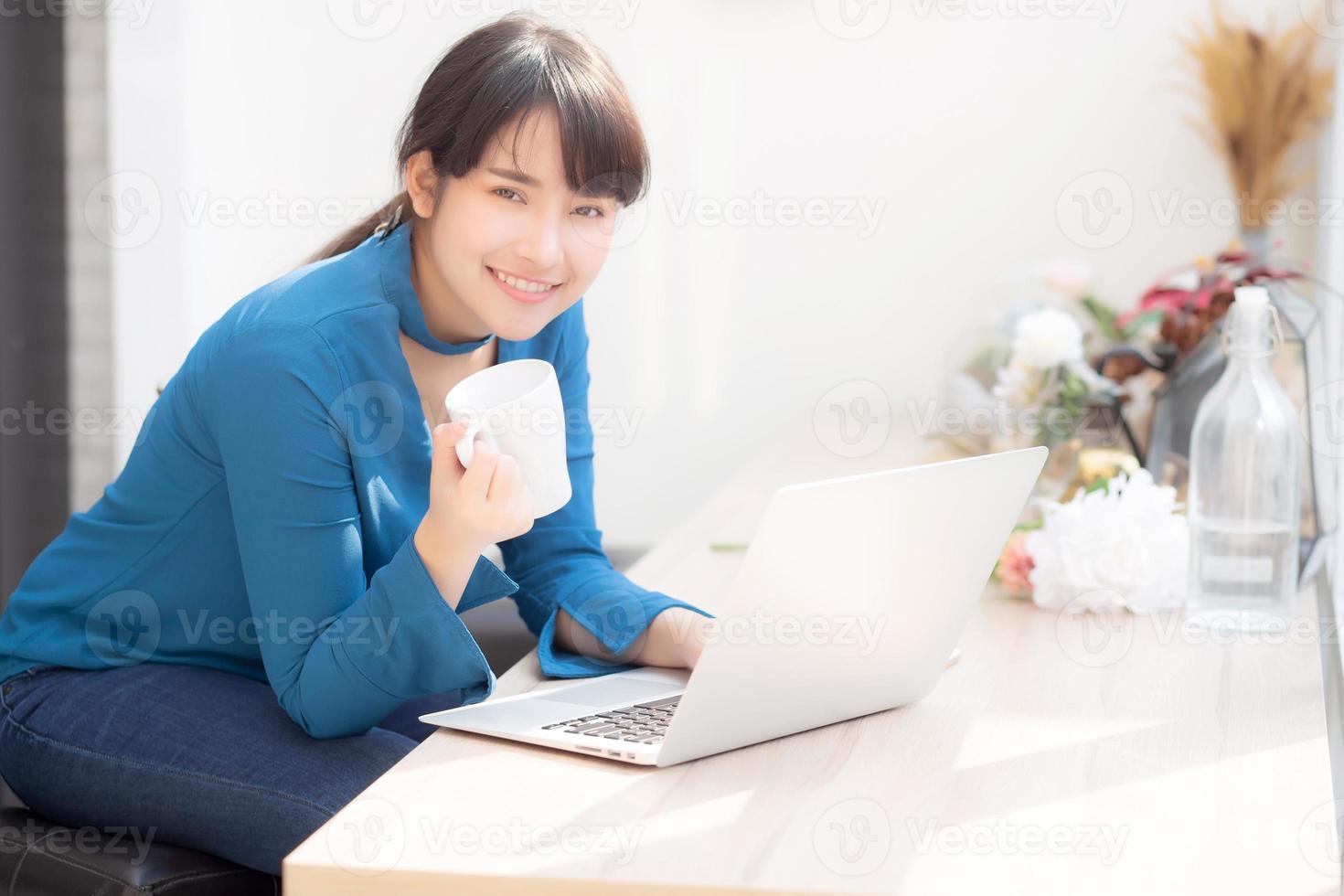 belle jeune femme asiatique indépendante souriante travaillant et sur un ordinateur portable au café du bureau avec une fille professionnelle, asiatique utilisant un ordinateur portable et buvant du café, des affaires et un concept de style de vie. photo