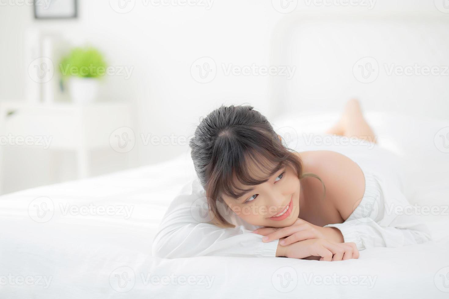 beau portrait jeune femme asiatique allongée et souriante au réveil avec le lever du soleil le matin, beauté jolie fille heureuse et joyeuse reposant sur le lit dans la chambre, mode de vie et concept de détente. photo