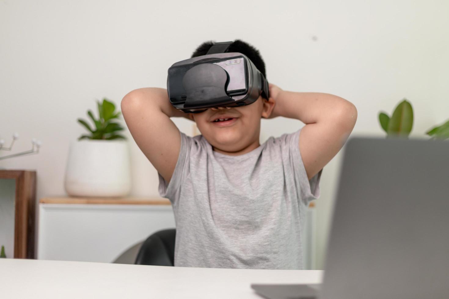 petit garçon asiatique avec des lunettes vr étudiant les sciences à la maison, un étudiant curieux porte un casque de réalité virtuelle pour étudier les sciences à la maison étude en ligne apprentissage futuriste du style de vie photo