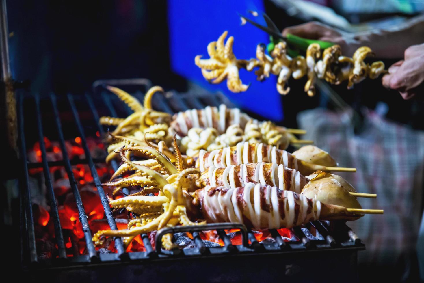 vendeur de calmars grillés dans l'alimentation de rue locale à yaowarat road célèbre lieu touristique en thaïlande photo