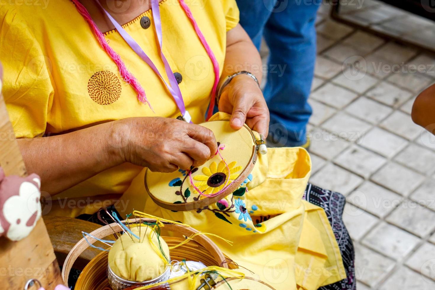 les mains en gros plan des dames font la démonstration de la couture et de la décoration de vêtements par un cadre de broderie pour les étudiants en classe de travaux ménagers. photo