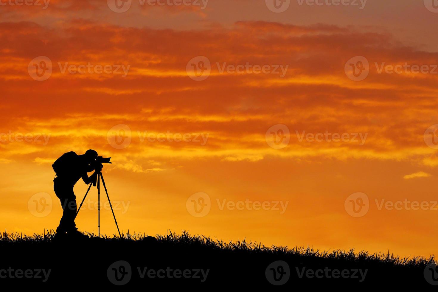 la silhouette d'un photographe professionnel se concentre sur la prise de vue dans une belle prairie. photo