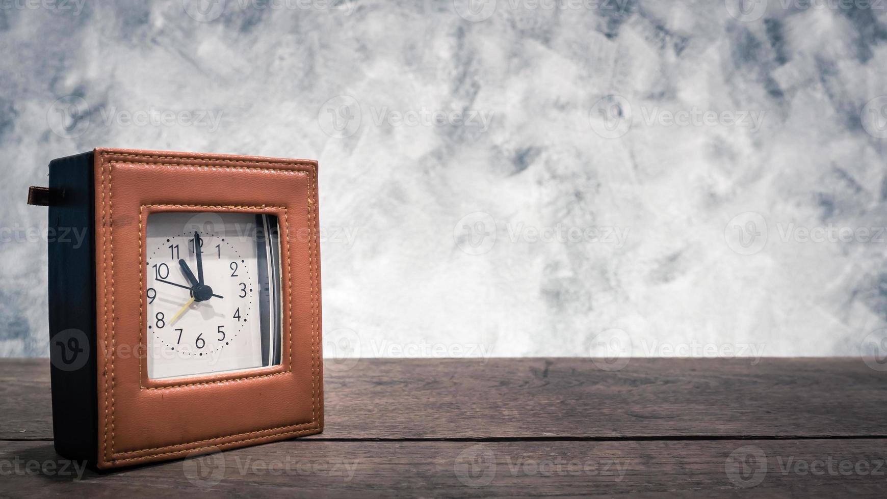 horloge sur la table en bois avec fond de mur vintage. espace libre pour votre texte. photo