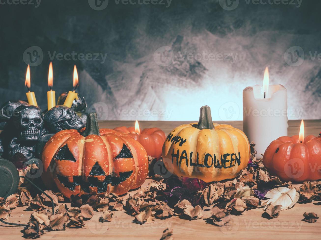 citrouilles d'halloween aux chandelles et crânes sur fond sombre. photo