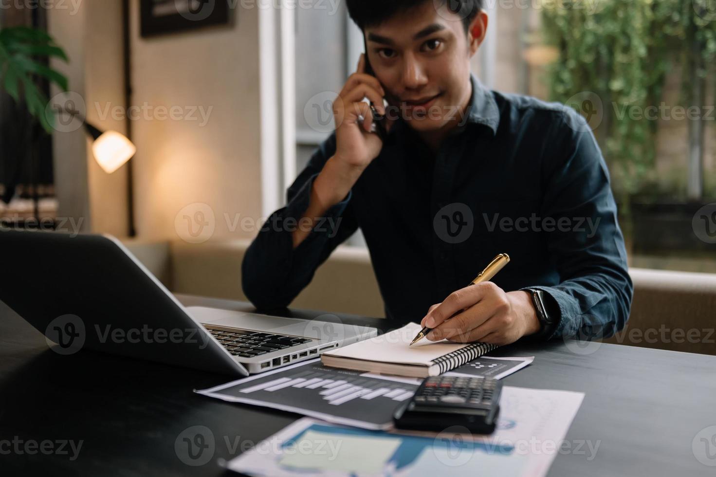 homme comptant des pièces sur la calculatrice en prenant de la tirelire. main tenant un stylo travaillant sur une calculatrice pour calculer sur le bureau le coût au bureau à domicile. photo