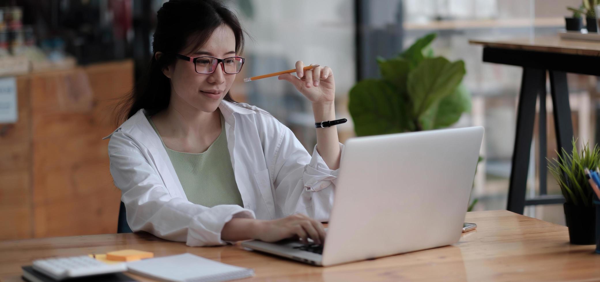 charmante femme d'affaires asiatique assise travaillant sur un ordinateur portable au bureau. photo