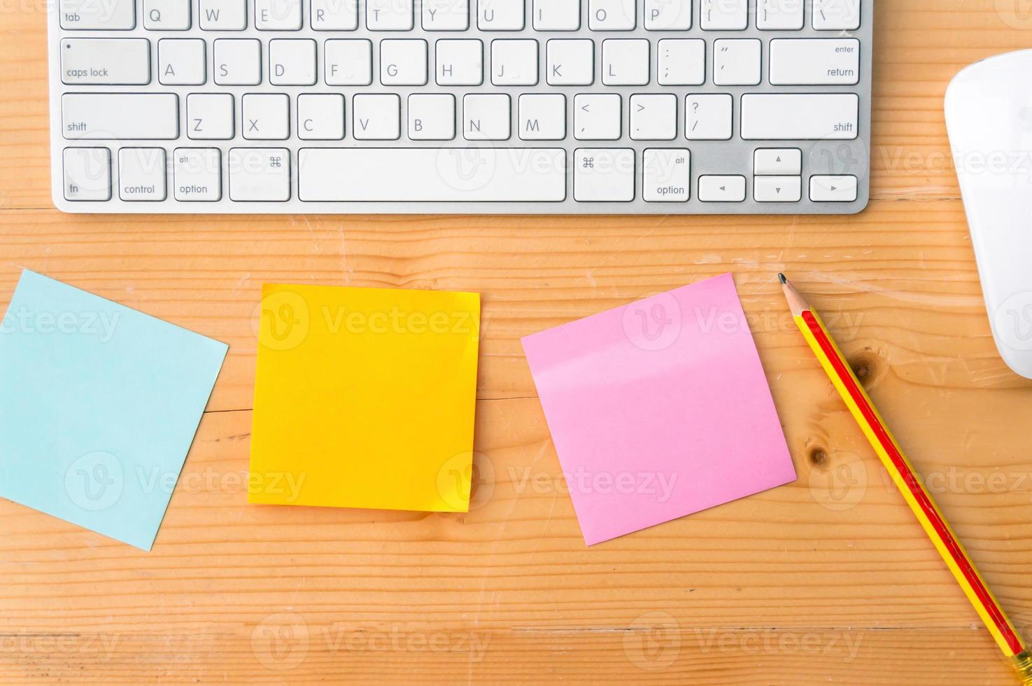 espace de travail vue de dessus avec notes autocollantes colorées, crayon, clavier et souris sur fond de table en bois. photo