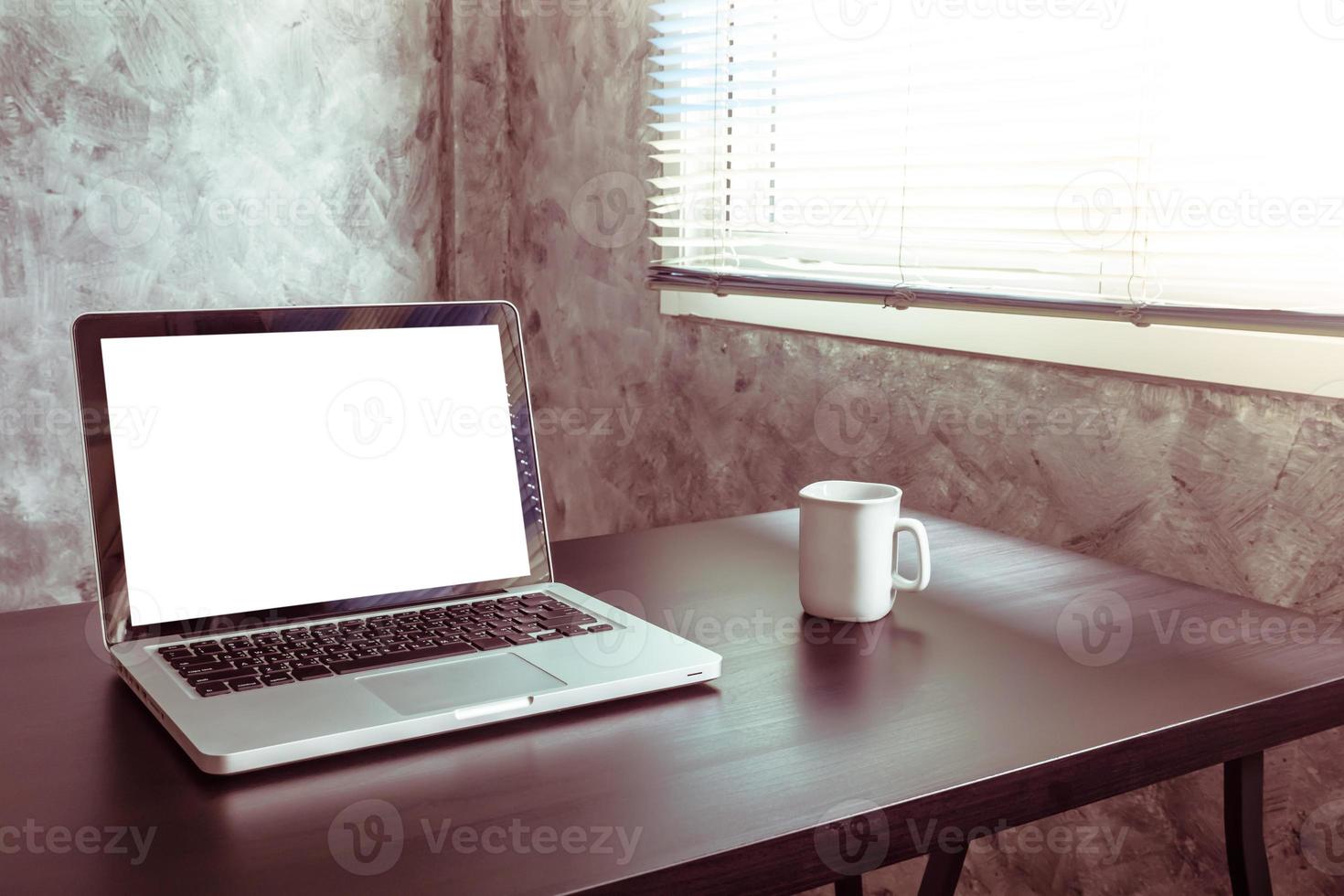 ordinateur portable avec écran blanc vierge, tasse de café blanche sur le bureau, ton vintage photo