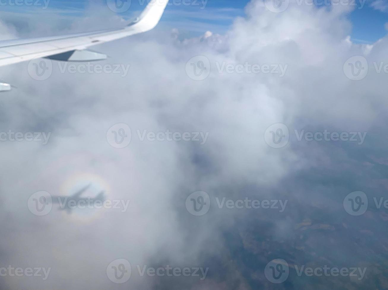 vue de la fenêtre de l'avion sur les nuages avec ombre et arc-en-ciel photo