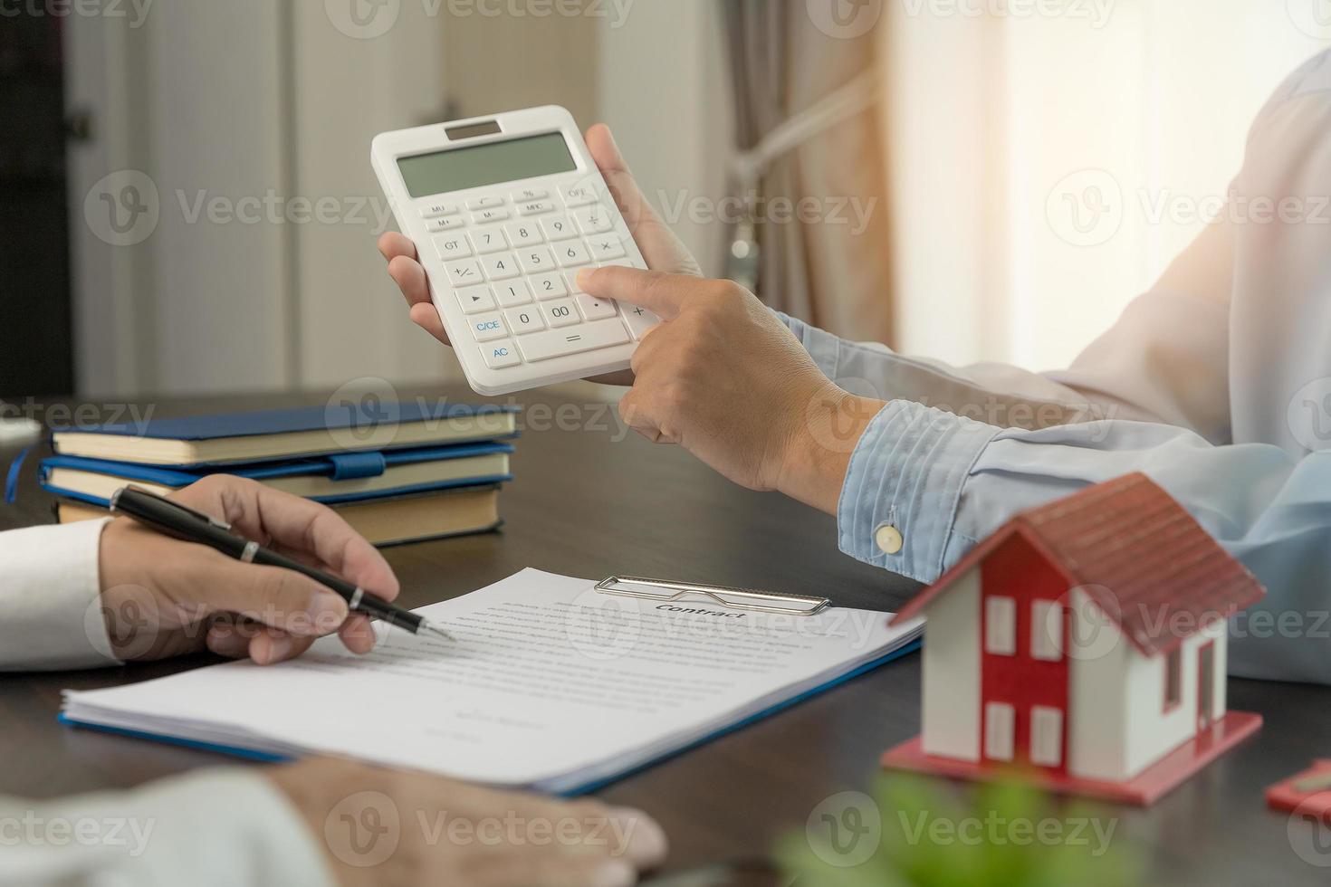 agent de courtage immobilier présentant et consultant au client pour la prise de décision signant un accord de formulaire d'assurance, modèle de maison, concernant l'offre de prêt hypothécaire et l'assurance habitation. photo