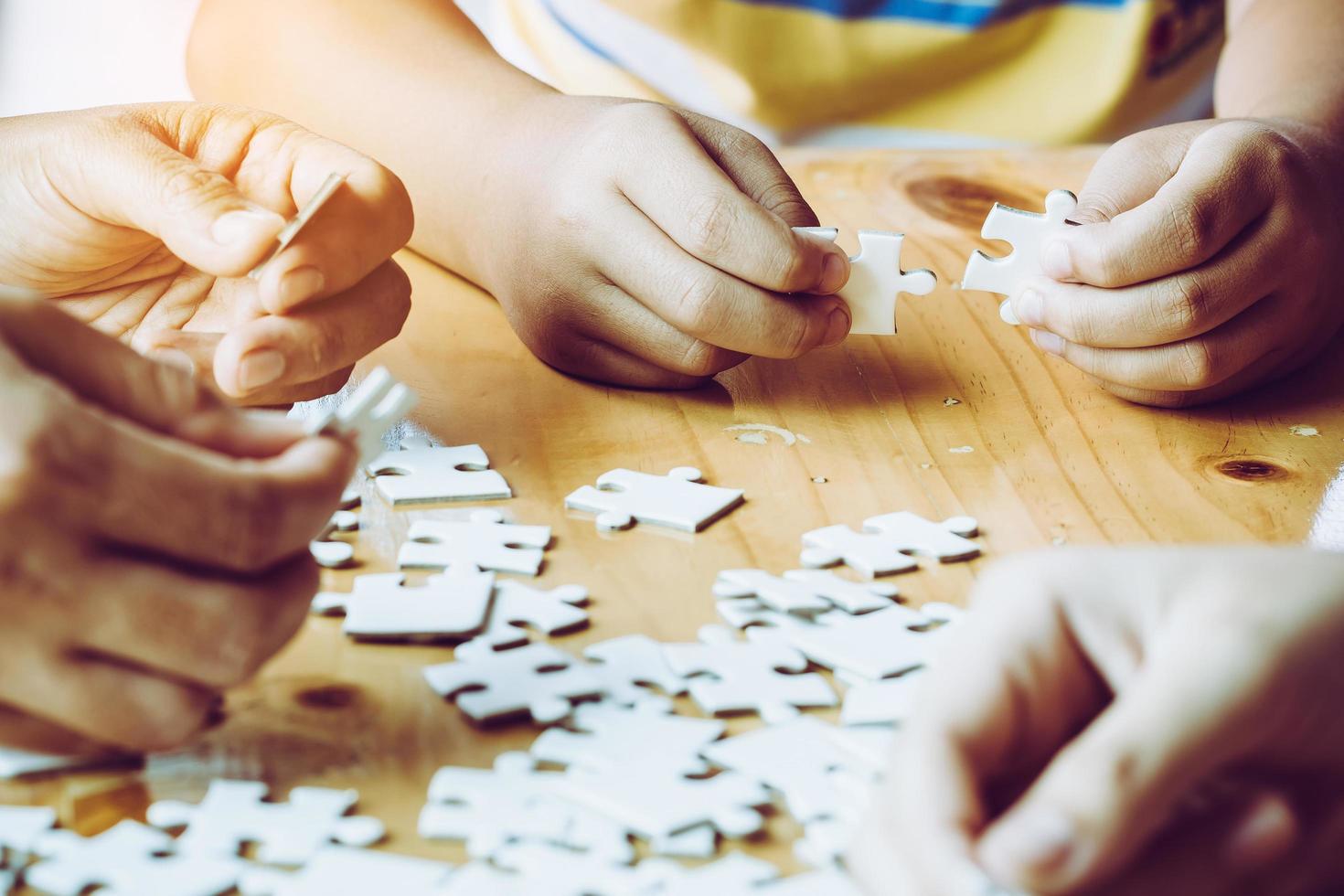 mains d'une personne petit enfant et parent jouant ensemble au jeu de pièces de puzzle sur une table en bois à la maison, concept de loisirs en famille, jouer avec le développement, l'éducation et le plaisir des enfants. photo