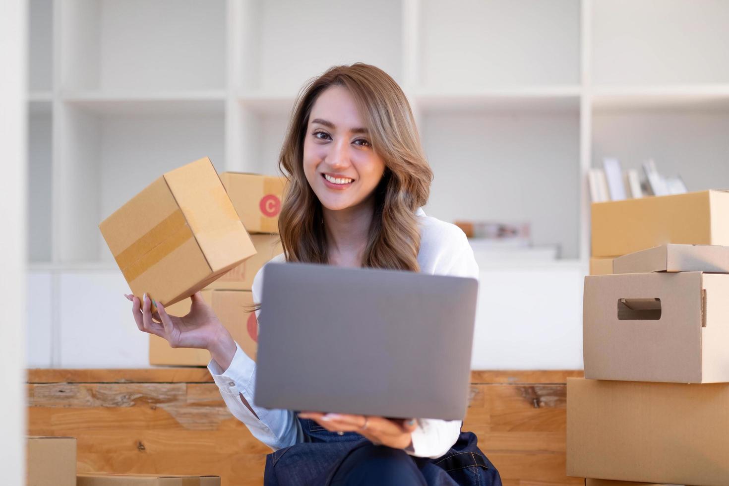 portrait d'une jeune femme asiatique sme travaillant avec une boîte à la maison le lieu de travail. propriétaire de petite entreprise de démarrage, entrepreneur de petite entreprise sme ou entreprise indépendante en ligne et concept de livraison. photo