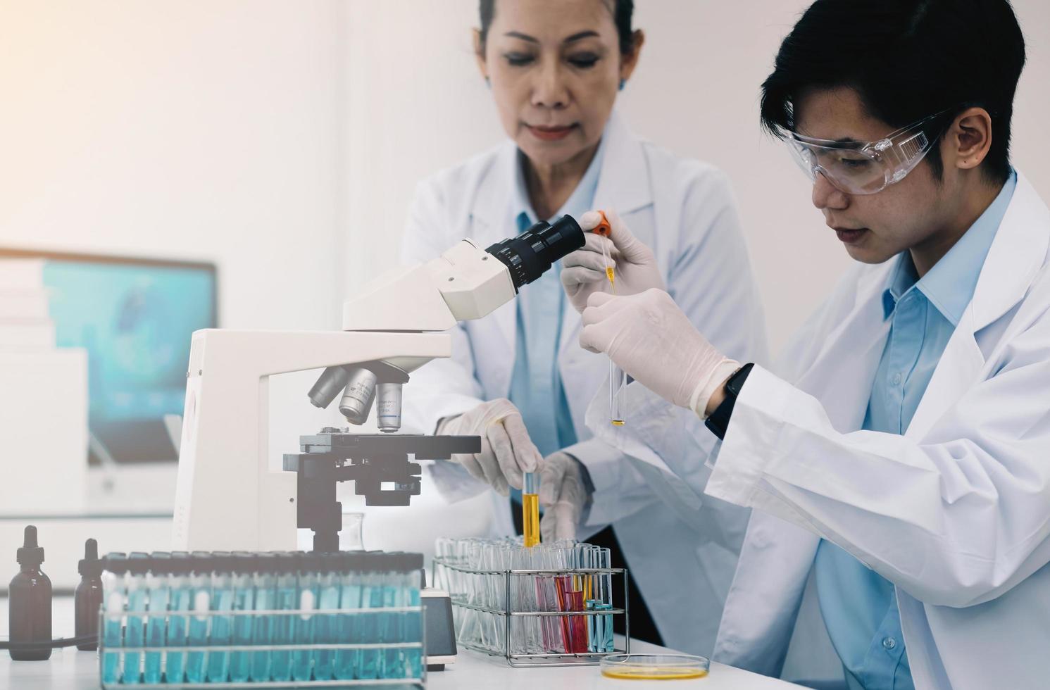 chercheurs en soins de santé travaillant dans un laboratoire de sciences de la vie. jeune chercheuse et superviseur masculin principal préparant et analysant des lames de microscope dans un laboratoire de recherche. photo