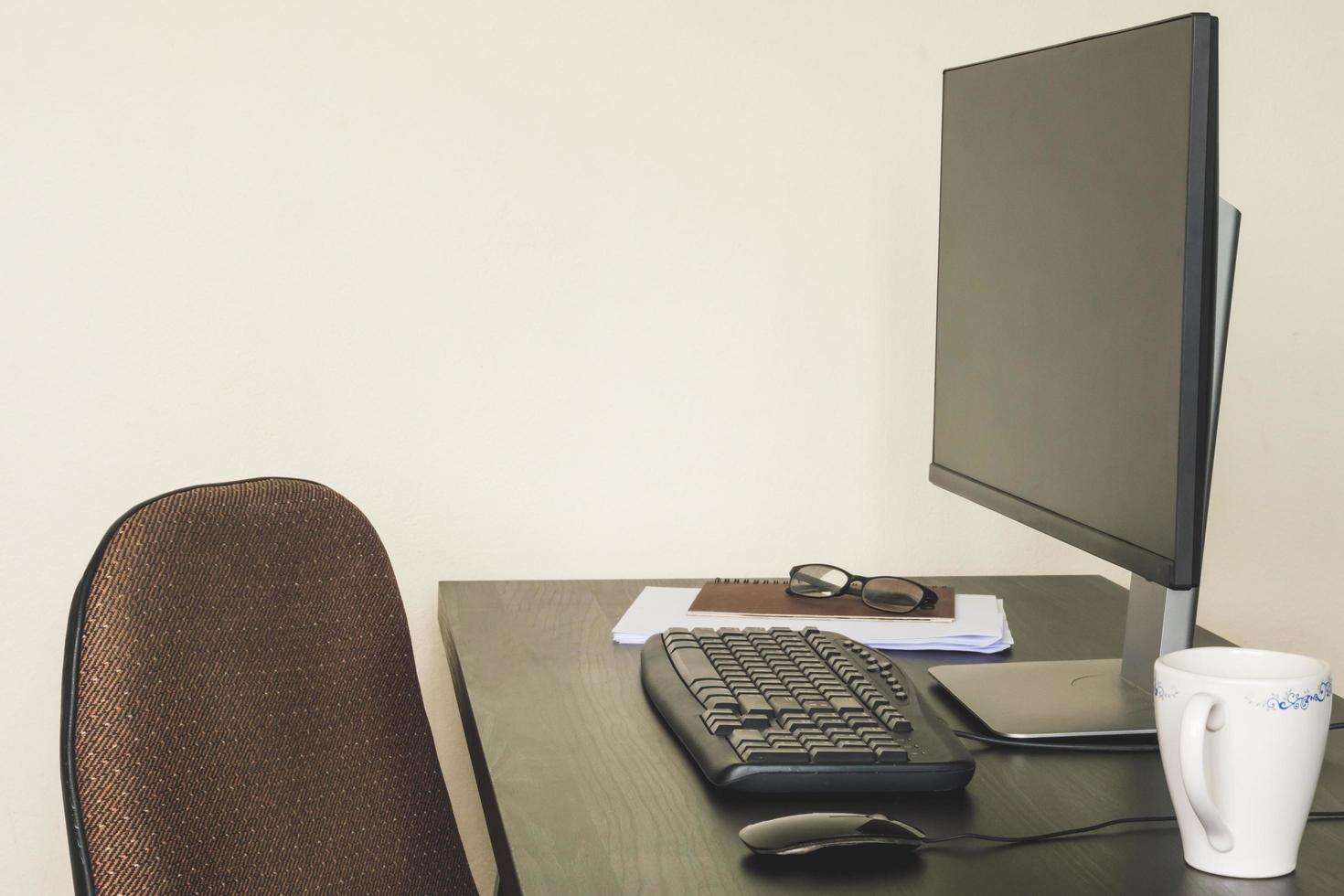 ordinateur avec document, verres et tasse à café sur le bureau. photo