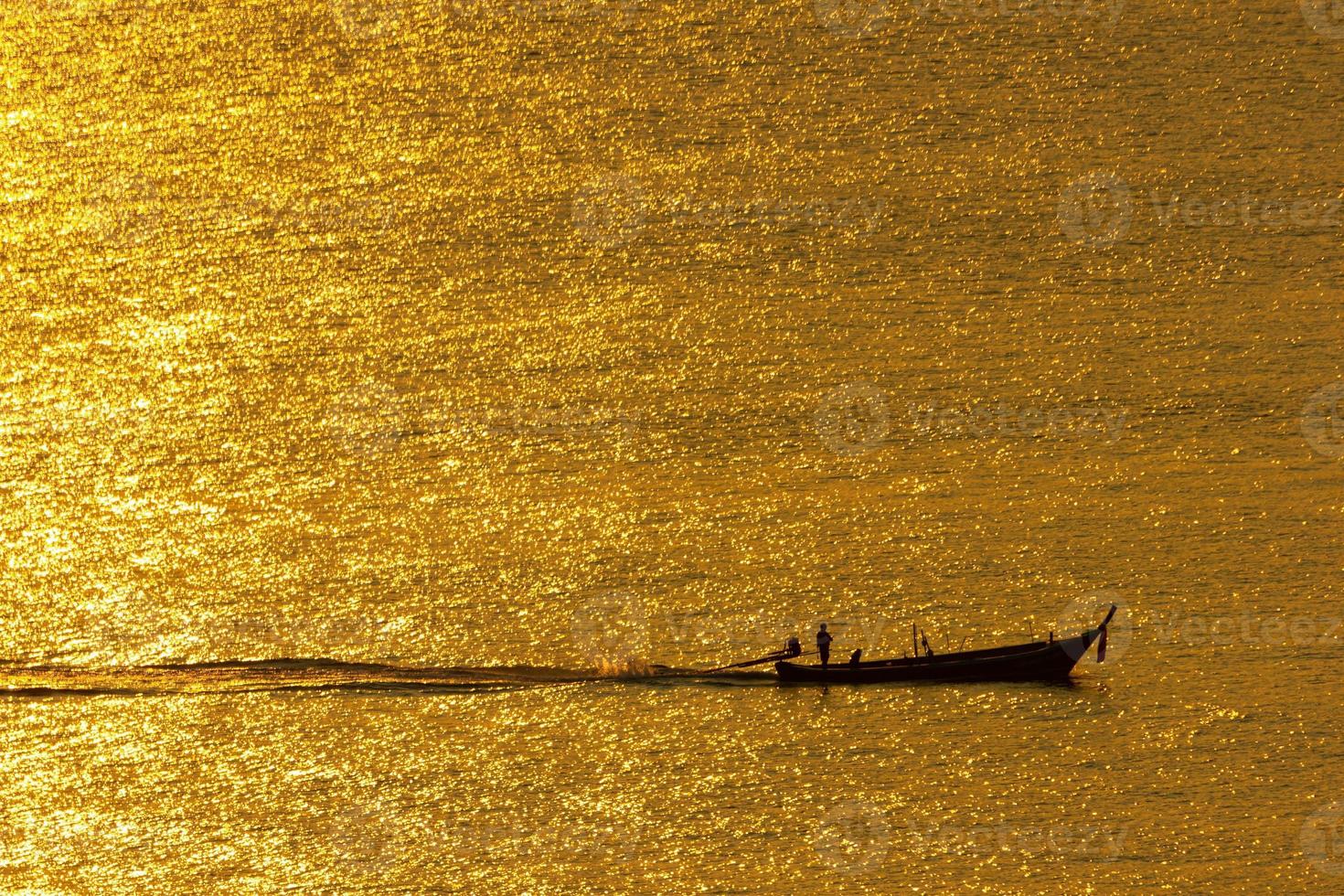 le coucher du soleil, la surface de la mer reflète la lumière du soleil en or. le navire traversa la surface scintillante de la mer. photo