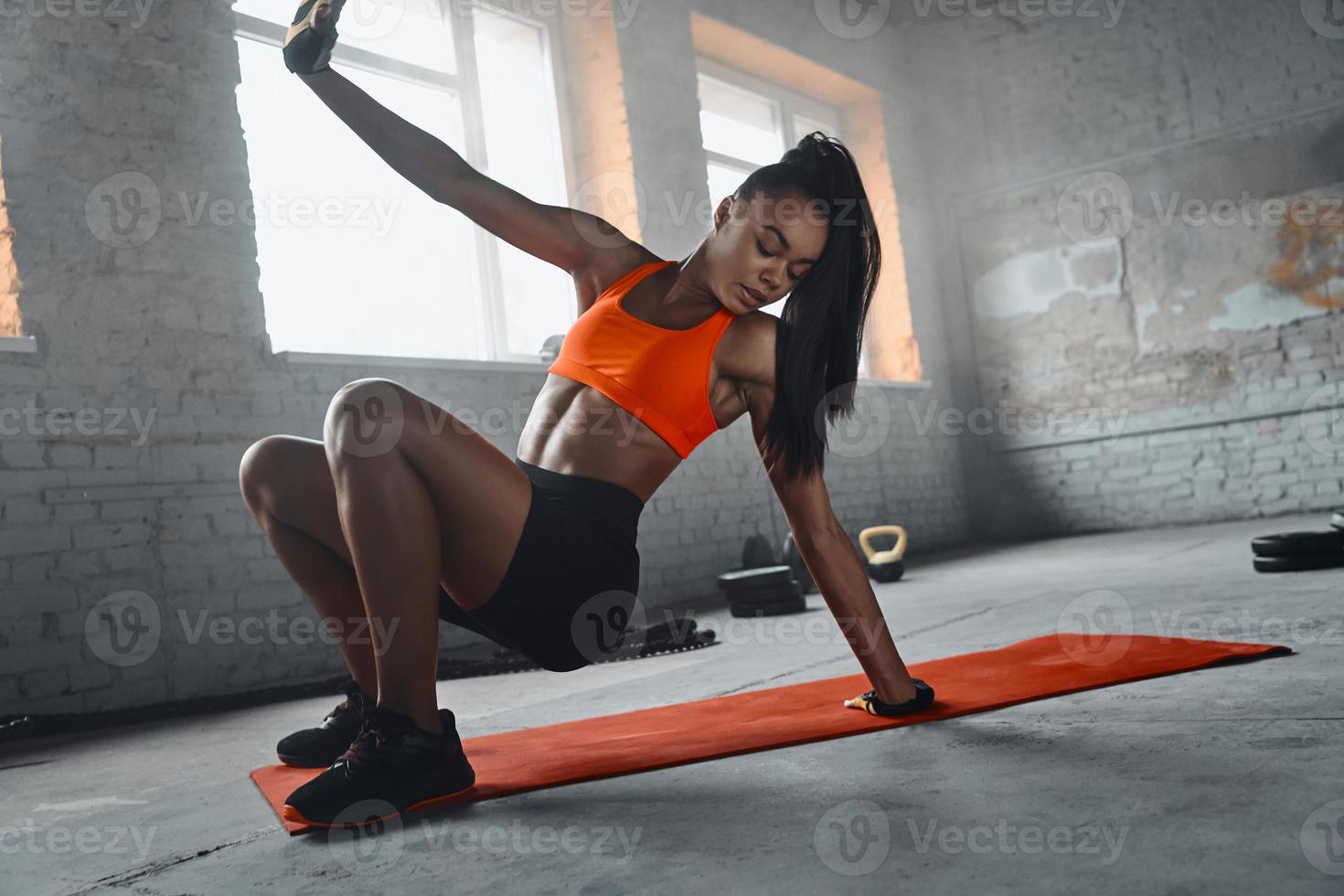 belle jeune femme africaine faisant de l'exercice sur un tapis dans la salle de sport photo