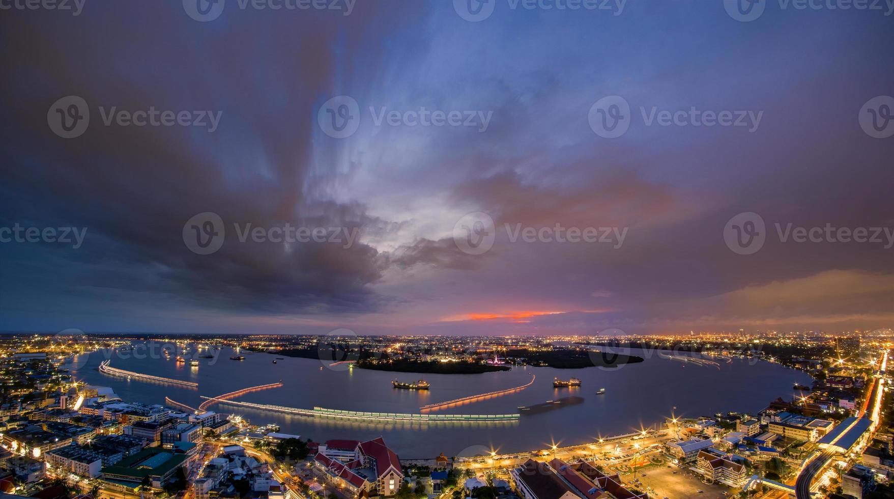 lampadaires et éclairage des rues des maisons résidentielles de la banlieue au coucher du soleil, trafic de bateaux sur la rivière chao phraya, samut prakan, thaïlande photo