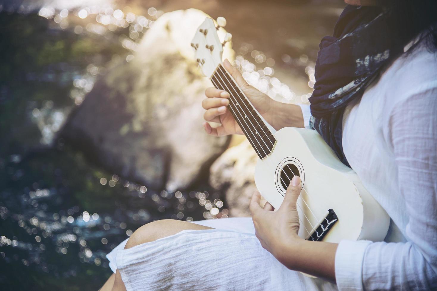 les femmes jouent du ukulélé nouveau à la cascade - style de vie des gens et des instruments de musique dans le concept de la nature photo