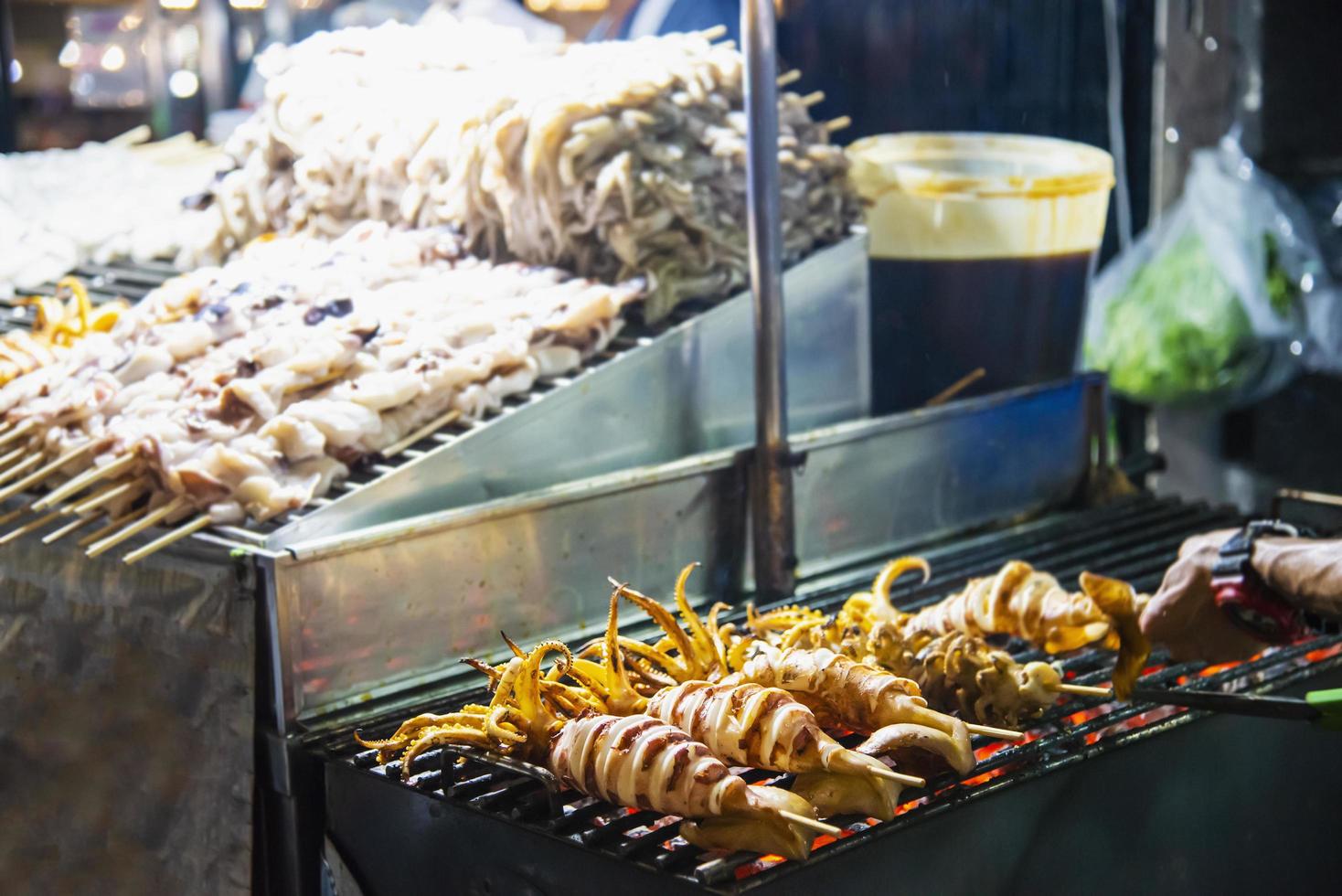 vendeur de calmars grillés dans l'alimentation de rue locale à yaowarat road célèbre lieu touristique en thaïlande photo