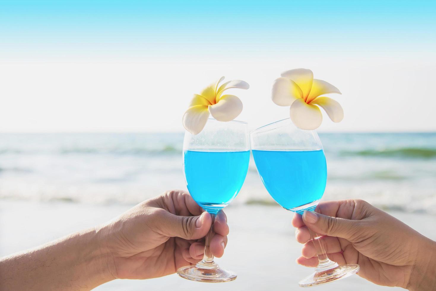 ccouple asiatique tenant une décoration de verre à cocktail avec fleur de plumeria avec fond de plage de mer vague - vacances de célébration de détente heureuse dans le concept de nature de mer photo