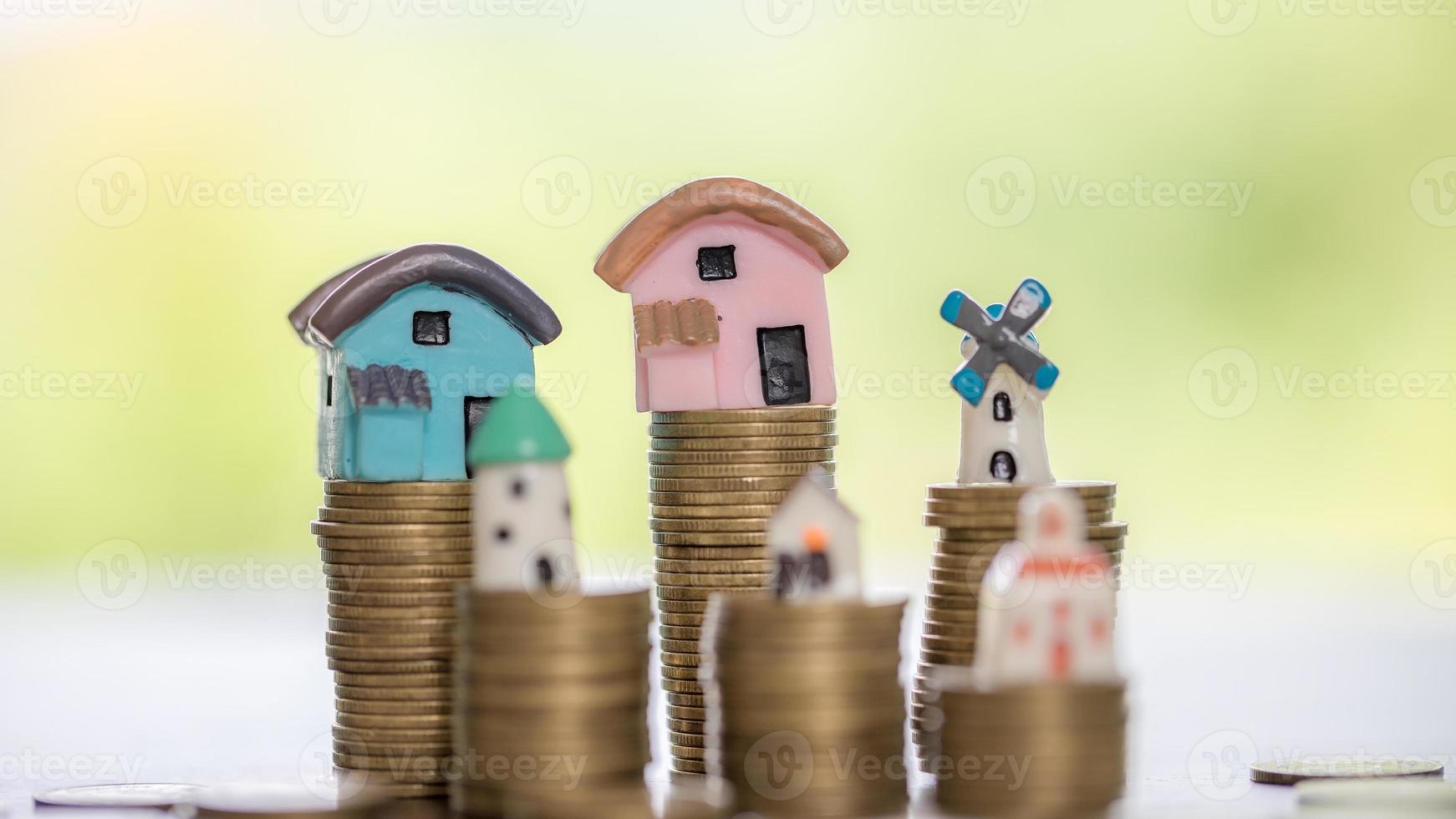 modèle de maison et piles de pièces d'argent avec fond nature flou. plans d'épargne pour la maison, le prêt, l'investissement, l'hypothèque, la finance et la banque sur le concept de maison. photo