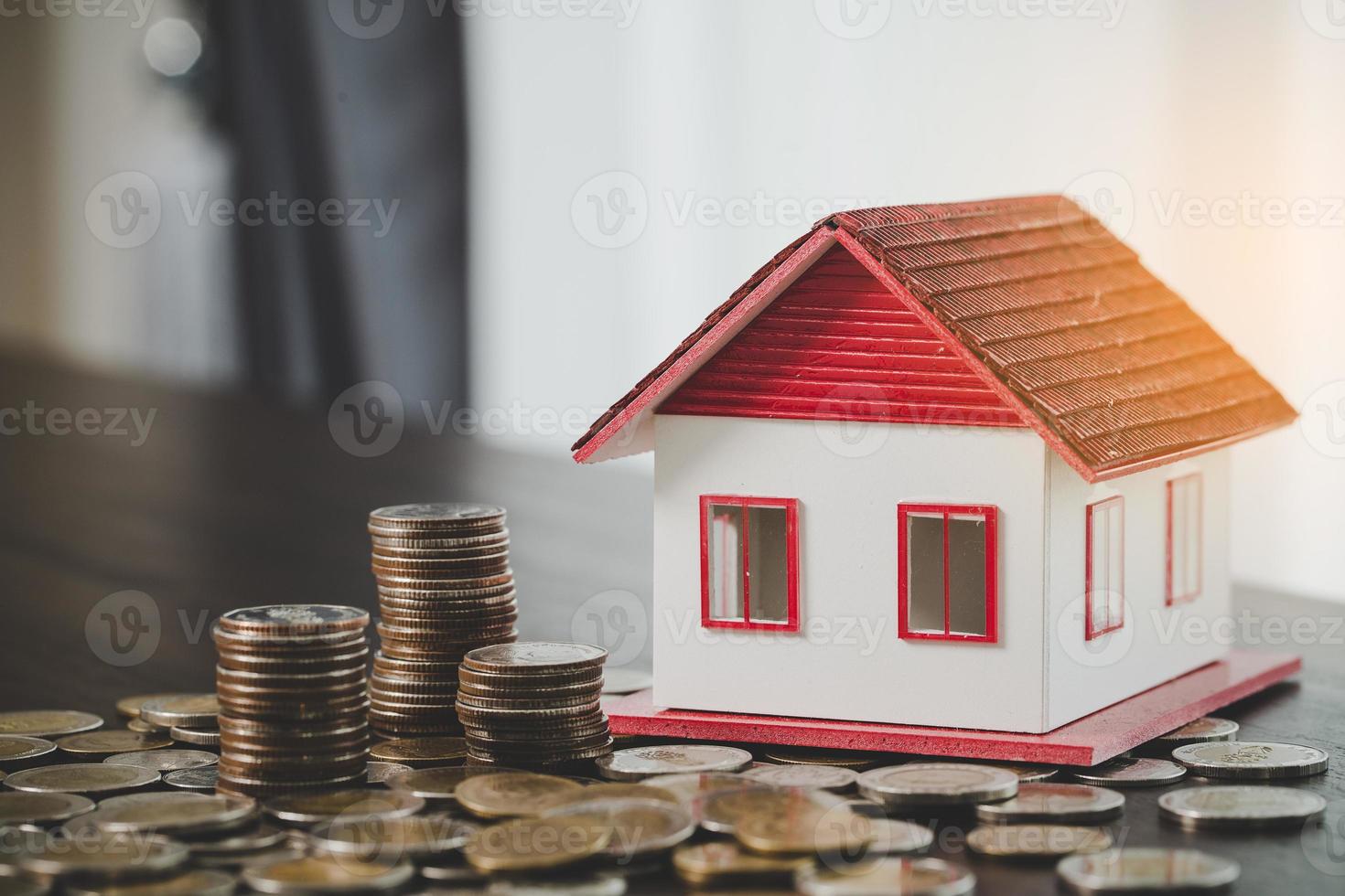 modèle de maison et piles de pièces d'argent sur fond de tableau flou. plans d'épargne pour la maison, le prêt, l'investissement, l'hypothèque, la finance et la banque sur le concept de maison. photo