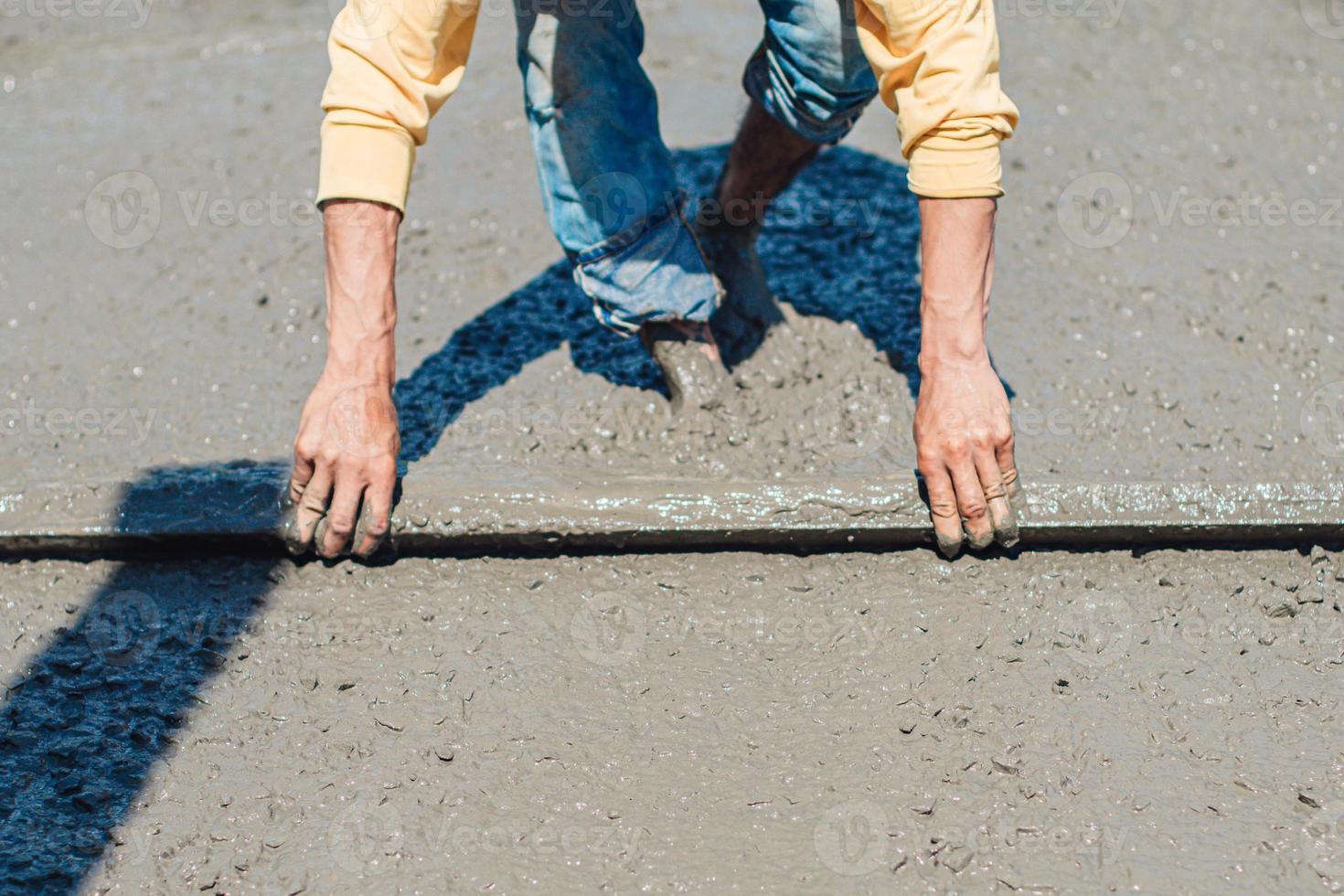 travailleur il utilise une truelle et nivelle le béton sur le sol du bâtiment.verser une dalle de béton photo