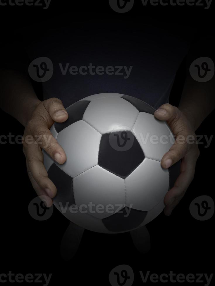 ballon de football dans la main masculine sur fond noir photo