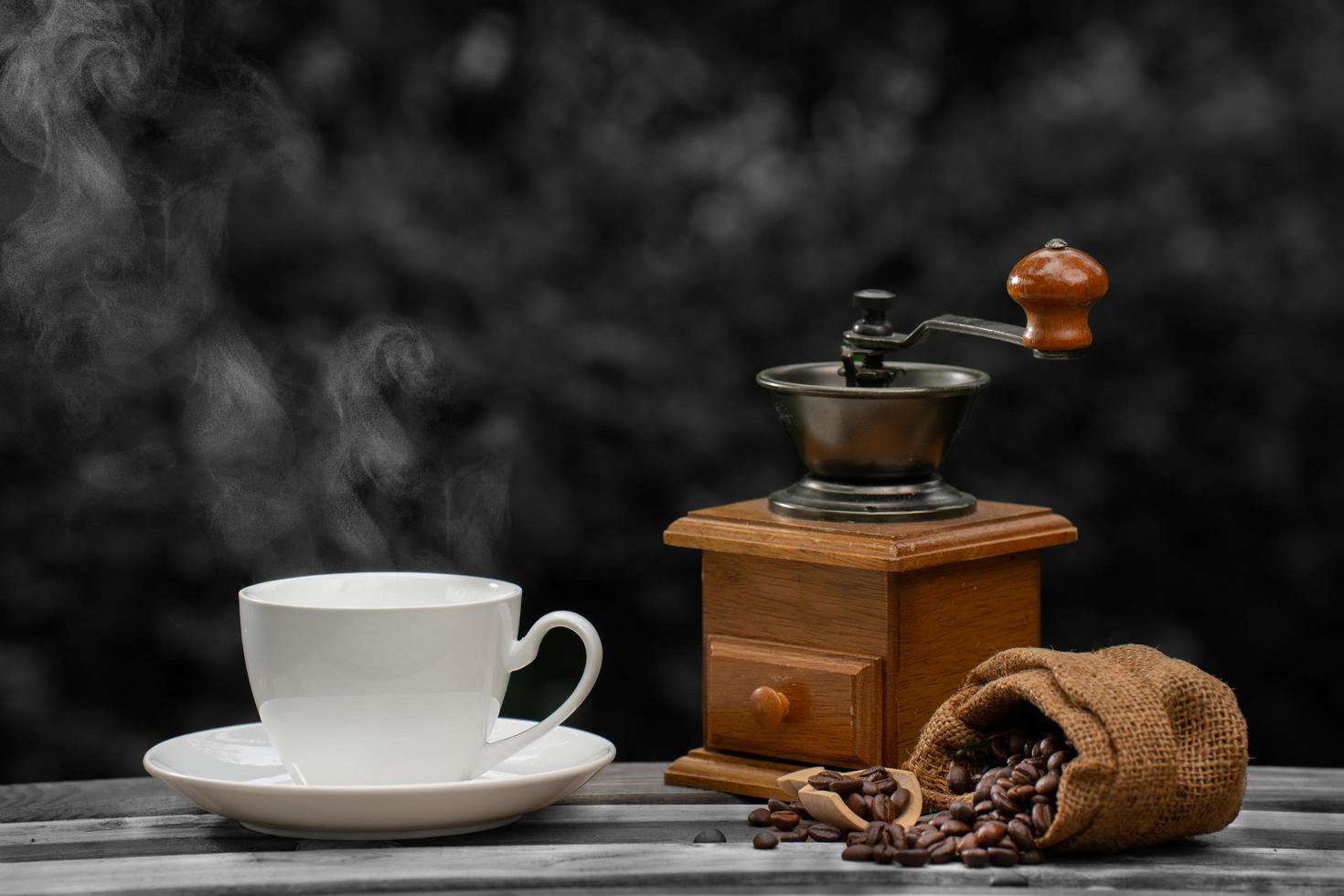 tasse à café avec un broyeur, grains de café noirs sur le vieux plancher en bois, gros plan de graines de café dans un fond naturel. photo