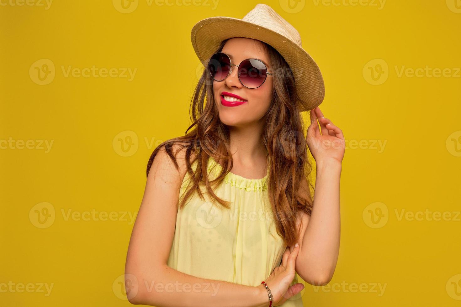 jolie femme élégante habillée de lunettes et d'un chapeau posant sur fond isolé et sourires, ambiance de vacances d'été, voyage, loisirs photo