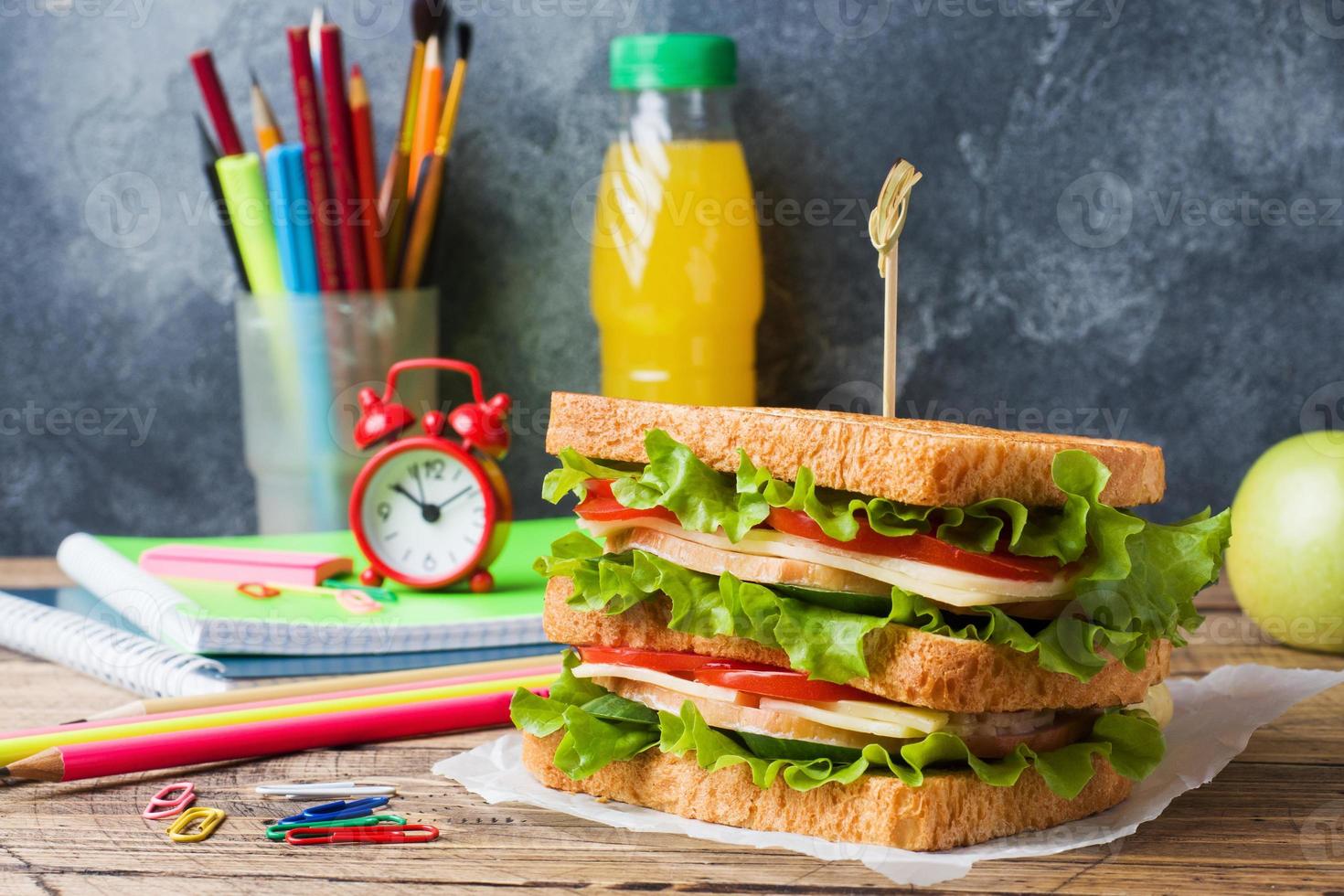 déjeuner sain pour l'école avec sandwich, pomme fraîche et jus d'orange. fournitures scolaires colorées assorties. espace de copie. photo