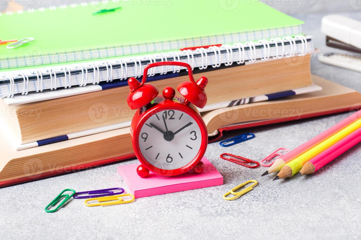 fournitures scolaires, cahiers de cahiers d'horloge crayons sur fond gris avec espace de copie. photo